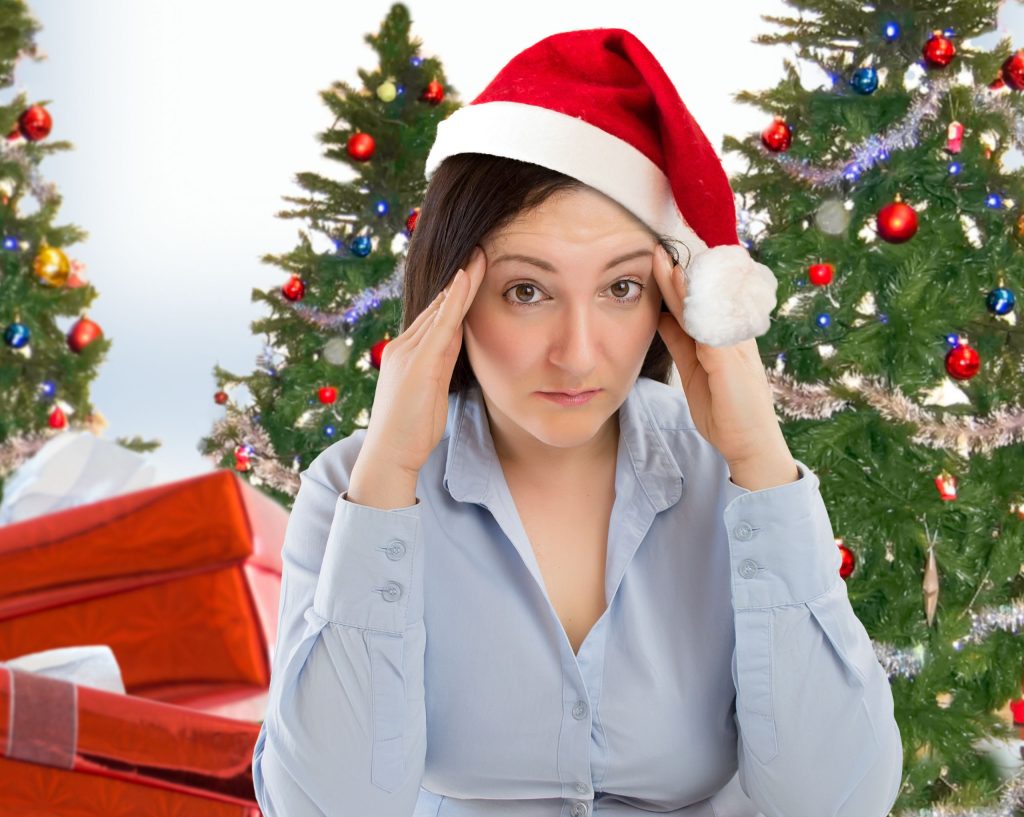 Stressed woman wearing a Santa hat with Christmas trees and gifts in the background